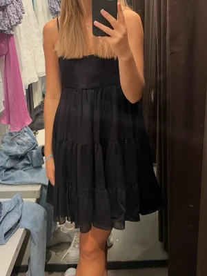Svart volangklänning från Zara - En superfin svart sommarklänning från Zara! Säljer då den blivit för liten. Klänningen är sparsamt använd! (Den har dock lite smånoppror upptil, se sista bilden) 