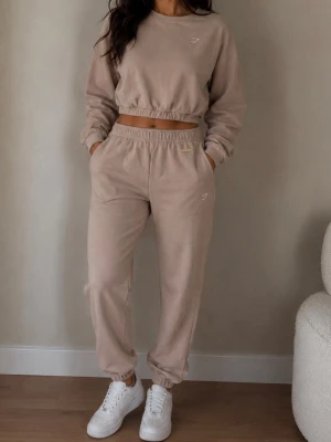 Beige loungewear set från Gymshark strl S - Säljer ett beige loungewear set från Gymshark med croppad sweatshirt och matchande byxor. Setet har resår i midja och benslut samt diskret logga på både tröja och byxa med Whitney Simmons . Mjukt material, perfekt för chill dagar hemma eller på träning 