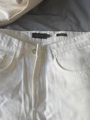 Vita raka jeans från massimo dutti - Säljer ett par vita jeans från massimo dutti med rak passform och klassisk femficksdesign. Jeansen har bälteshällor, knappgylf och är tillverkade i ett kraftigare denimtyg i bomull. Perfekta för en clean och stilren look.