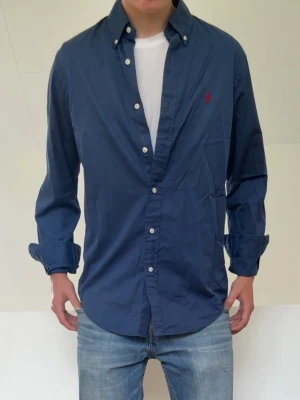 Mörkblå Ralph Lauren skjorta - Mörkblå Ralph Lauren skjorta sitter i strl M. Mycket bra skick utan nåra defekter och hör gärna av er vid frågor elr funderingar!!