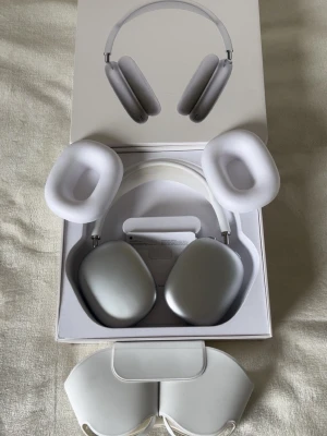 Apple AirPods Max silver hörlurar - Snygga Apple AirPods Max i silver med en stilren design. Over-ear-modell med mjuka öronkuddar och justerbart huvudband i mesh. Tillverkade i aluminium och rostfritt stål, med detaljer i vitt. Levereras med originalförpackning och smart case.