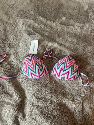 Helt oanvänd flerfärgad bikiniöverdel Calzedonia - Säljer en färgglad bikiniöverdel från Calzedonia med zigzag-mönster. Klassisk trekantsmodell med knyt i nacke och rygg. Perfekt för sommaren! Helt oanvänd och prislapp kvar✨😍