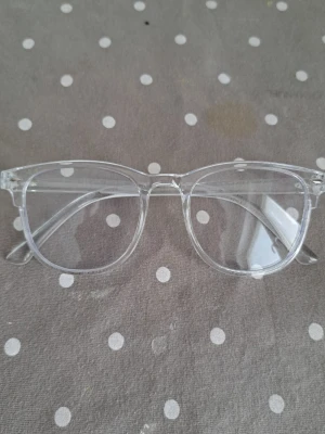 Transparenta solglasögon i retrostil - Säljer ett par stilrena solglasögon med transparent båge och klassisk retroform. Glasögonen har en modern och clean look som passar till många outfits. Perfekta för dig som vill ha en minimalistisk vibe.