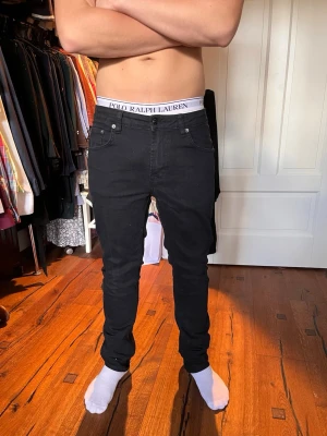 Svarta slim fit jeans herr - Säljer ett par svarta slim fit jeans med klassisk design och smal passform. Jeansen har normal midja och raka ben, perfekta för en stilren och modern look. Materialet är stretchigt för extra komfort.
