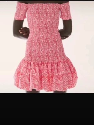 Trendig rosa mönstrad klänning HM - Söt rosa kortklänning med offshoulder och volangkant. Klänningen har ett vitt bladmönster och smockad överdel som ger en bekväm passform. Perfekt för sommarens alla tillfällen.