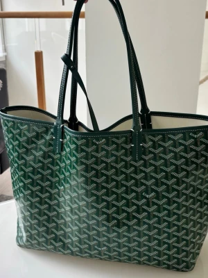 Grön shoppingväska  - Snygg grön shoppingväska med det klassiska mönstret i vitt och beige. Väskan har använts 2 gånger och är i nytt skick. 