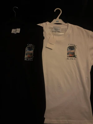 Casa Blanca La Night t-shirt med tryck - Snygg t-shirt från Casa Blanca med färgstarkt tryck av stadsmotiv och palm på bröstet. Finns i både svart och vit. Klassisk passform och rund halsringning. Tillverkad i mjuk bomull för skön känsla hela dagen. HELT NYA & OANVÄNDA. 320kr st eller båda för 600