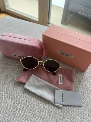 MiuMiu solglasögon  - MiuMiu solglasögon i komplett set, box, fodral, booklet och putsduk. Bruntonade glas + guldfärgade bågar. Logga på båda sidor. Bra skick, sparsamt använda, inga repor. Modell:SMU52Y🫶🏼🌸