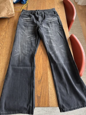 Blå stone wash bootcut jeans - Säljer ett par blå stone wash jeans med bootcut passform. Jeansen har en klassisk femficksdesign och slitna detaljer som ger en cool vintagekänsla. Perfekta för dig som gillar en avslappnad och trendig stil. W32 L34
