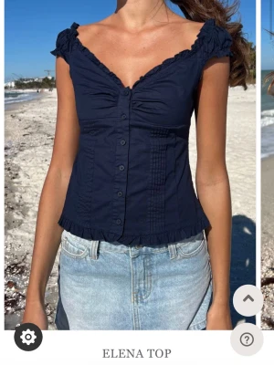 Mörkblå topp - Söt mörkblå topp med knappar framtill, volangkant vid ärmar och nederkant samt lätt rynkade detaljer vid bysten. Från brandy Melville. Stl xs/s💕använd 2 gånger så skicket är som nytt! 