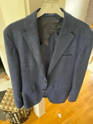 Mörkblå kavaj från Polo Ralph Lauren - Stilren mörkblå kavaj från Polo Ralph Lauren med klassisk passform och två knappar framtill. Kavajen har diskret struktur i tyget, tre fickor och helfodrad insida. Perfekt för dig som vill ha en tidlös och snygg look. Nypris: runt 3000, mitt pris: 599! Hör av er vid frågor! 