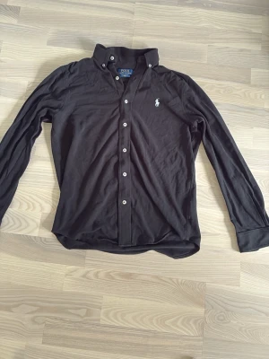 Svart skjorta från Polo Ralph Lauren - Ralph Lauren meshfeatherweight skjorta i storlek S, bra skick inget slitage. Köpt på thernlunds för 1799kr