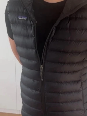 Svart dunväst från Patagonia M - Snygg svart dunväst från Patagonia i storlek M. Västen har quiltad design, hög krage och dragkedja framtill. Är 180cm lång på bilden, skick - 9/10. Nypris är 2 200kr, så ett väldigt bra pris!Kan dock alltid gå ner i pris vid snabb affär 😁🤝. Hör av er vid minsta lilla fundering eller fråga!