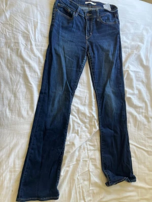 Levi's 715 Bootcut jeans blå 29 - Snygga blå Levi's 715 Bootcut jeans med klassisk femficksmodell och bootcut-ben. Jeansen har en mörk tvätt med lätt slitning och kontrastsömmar. Perfekta för dig som gillar en tidlös och avslappnad stil.