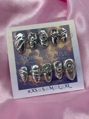 Zira (XS);Short Almond - Unika silvriga press-on naglar från Von Juan Nails med cool 3D-design och detaljer som stjärnor och ringar. Naglarna har en kort till medellång form och är handgjorda i akryl. Perfekt för dig som vill ha ett edgy och futuristiskt look.