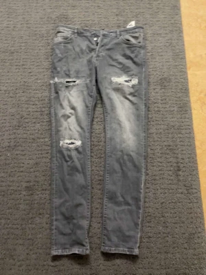 Grå slitna jeans från Dsquared2 - Säljer ett par grå jeans från Dsquared2 med slitningar och hål på låren och knäna. Jeansen har en smal passform och klassisk femficksdesign. Materialet är denim i bomull och de har en cool, tvättad look.