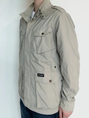 Woolrich Jacka - Snygg och eftertraktad field jacka från Woolrich! Fint skick inga defekter. Storlek L, modellen är ca 182, 70kg, lite för stor. Kontakta mig för fler frågor och funderingar!