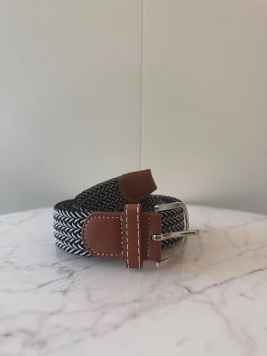 Svart vitt flätat bälte - Tja säljer helt nytt klassiskt svenskt flätat bälte från Bältgallerian i storlek 105cm i längd och 3,5cm i bredd. Dem är i ett elastiskt material och finns i flera olika färger i min profil.