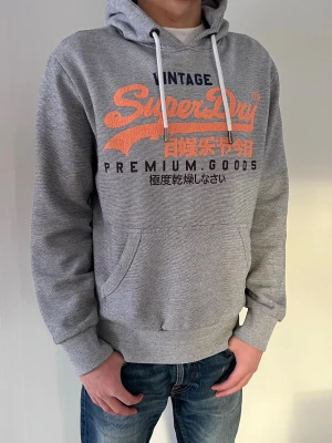 Grå Superdry hoodie  - Snygg och lite sällsyntare hoodie från superdry. Skriv vid minsta fundering! Storlek M men passar även lite mindre