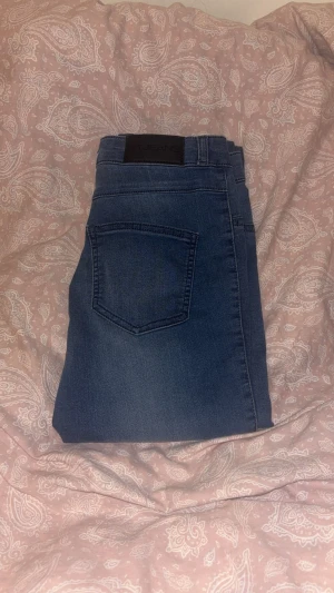 Blå jeans från Fit Jeans - Snygga blå jeans från Fit Jeans med klassisk femficksdesign och en stilren läderpatch bak i midjan. Jeansen har en rak passform och är tillverkade i ett mjukt denimtyg som ger en bekväm känsla. Perfekta för dig som gillar en enkel och tidlös look. Passar som S. Är 1,70cm lång och passar perfekt.