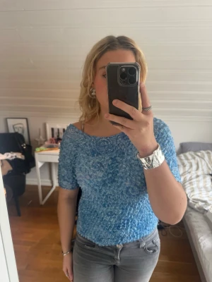 Blå ribbad topp med offshoulder - Supersöt blå topp med ribbad struktur. Toppen är stretchig och har korta ärmar. Perfekt för dig som gillar en unik och trendig look. Ingen synlig logga eller märke. Skulle gissa på att de är en M men går nog säkert och ha en storlek mindre eftersom den är strechig i materialet. 