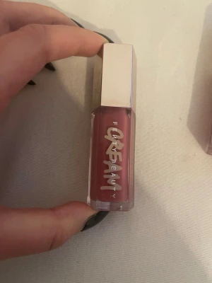Fenty Beauty Gloss Bomb Cream Cupcakin' - Säljer ett Fenty Beauty Gloss Bomb Cream i färgen Cupcakin'. Läppglanset har en mjuk rosa ton. Den säljs inte längre. Köpt för ungefär 310kr. Den är nästan nya bara använt några få gånger men färgen passar inte mig