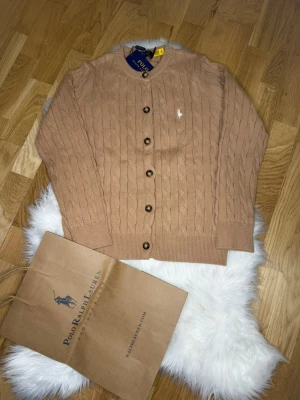 Stickad Polo Ralph Lauren Kofta - En beige stickad kofta som använts 2 gånger (men etiketterna sitter kvar). Påsen ingår!