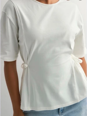 Tie waist tee Nelly  - Säljer denna vita tröjan med knyte i midjan från Nelly, endast använd en gång! I storlek xxs!💕