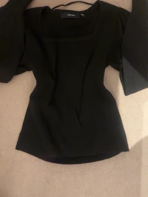 Svart långärmad topp från Vero Moda - Snygg svart långärmad topp från Vero Moda med fyrkantig urringning. Modellen är figurnära och har långa ärmar. 