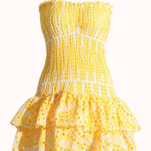 Gul och vit kortklänning Design By Amor - Superfin kortklänning från Design By Amor i storlek S. Klänningen är inte använd! Klänningen är axelbandslös med smockad överdel och har volangdetaljer nedtill. Färgen är gul och vit med broderat mönster och coola prickar. Den är i jättebra skick och är aldrig använd 