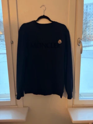 Svart sweatshirt från Moncler - Snygg svart sweatshirt från Moncler med rund halsringning och diskret Moncler-logga på bröstet. Tröjan har långa ärmar och en klassisk passform, perfekt för en stilren och avslappnad look.