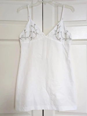 Vit Zara klänning med strass - Superfin vit Zara klänning med strass på bysten och broderade blommor på bysten! Den har en dragkedja i ryggen och är helt ny med lappen kvar! Säljer då den tyvärr är lite stor i bysten på mig 💗  Perfekt till ett white party eller liknande!!  Kika gärna in mina andra plagg