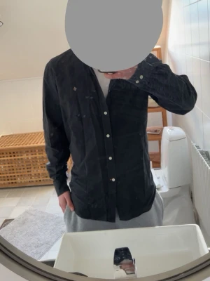 Morris skjorta - Storlek 44 men motsvarar M/S Säljer en svart skjorta med klassisk krage och vita knappar. Skjortan har lång ärm och en liten broderad detalj på bröstet. Perfekt till jeans eller chinos för en clean look. Pris kan diskuteras vid snabb affär!