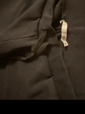 Svarta mjukisbyxor med dragsko XS - Svarta mjukisbyxor i klassisk modell med resår och dragsko i midjan. Byxorna har raka ben och är tillverkade i ett mjukt och bekvämt material, perfekt för chill dagar. Enkla att matcha med hoodies eller t-shirts. Helt ny köpt för 250. Går ner i pris vid snabb köp 