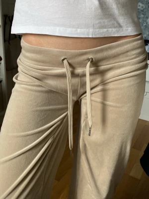 Beige mjukisbyxor från Gina Tricot - Säljer ett par beige mjukisbyxor från Gina Tricot i mjukt velourmaterial. Byxorna har bred resår i midjan och dragsko med snören framtill. 
