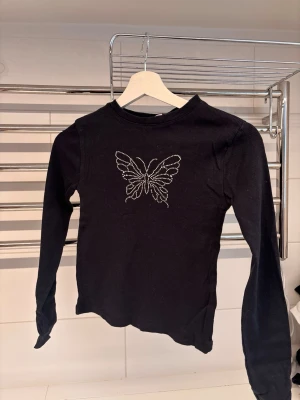 Långarmad tröja - Långarmad tröja med en glitterfjäril. Storlek 152