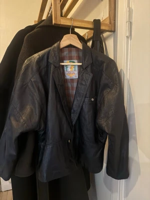 Svart vintage skinnjacka  - Säljer min super snygga svarta skinnjacka i blazer-modell från Läder AB. Jackan har klassisk krage, knappstängning och fickor fram. Köpte den på en märkes vintage butik i Italien, nypris ca 1600 kr