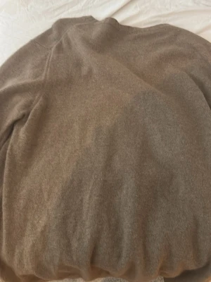 Beige stickad tröja Oscar Jacobson - Säljer en beige stickad tröja från Oscar Jacobson. Tröjan har rund halsringning och är tillverkad i Italien. Mjuk och klassisk modell med ribbade muddar vid hals, ärmslut och nederkant. Perfekt för lager-på-lager-stil.