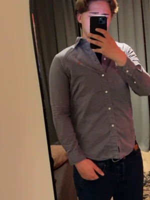 Ljuslila skjorta från Ralph Lauren - Säljer en ljuslila skjorta från Ralph Lauren med klassisk krage och knäppning framtill. Skjortan har lång ärm och den ikoniska röda logotypen broderad på bröstet. Perfekt för dig som gillar stilrena och snygga plagg.