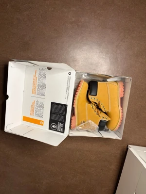 Timberland kängor  - Säljer ett par klassiska gula Timberland kängor med  och svart vadderad kant upptill. Kängorna har robust snörning och är tillverkade i slitstarkt läder. Perfekta för dig som vill sticka ut med en färgglad twist på en ikonisk modell.