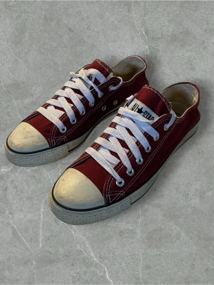 Röda Converse All Star låga sneakers | Storlek 40 - Klassiska röda Converse All Star sneakers med vit tåhätta och vita snören. Skorna har lågt skaft, canvasmaterial och gummisula. Perfekta för en avslappnad och cool stil. Ikonisk logga på plösen och metallöljetter för snörningen.