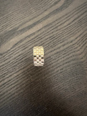 Edblad ring - Säljer en bred silverfärgad ring med flera rader av små gnistrande stenar i rutmönster. Ringen har en modern och chunky design som verkligen sticker ut. Perfekt för dig som gillar att glänsa och vill ha något unikt på fingret.