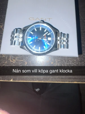 Silverfärgad Gant klocka med blå urtavla - Stilren klocka från Gant med silverfärgad länk och blå urtavla. Klockan har tydliga indexmarkeringar och klassisk design, perfekt för dig som gillar en tidlös accessoar. Metallarmbandet ger en exklusiv känsla och passar till många olika stilar.