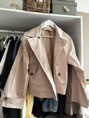 Beige kort trenchcoat med knappar - Beige trenchcoat från Only, använd fåtal gånger 