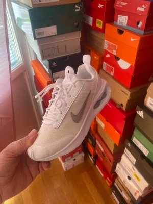 Vita Nike Air Max sneakers med snörning - Snygga vita sneakers från Nike med klassisk siluett och synlig luftdämpning i sulan. Skorna har vit mesh-överdel, vit sula och silverfärgad swoosh på sidan. Perfekta för dig som gillar stilrena och sportiga sneakers med modern känsla.