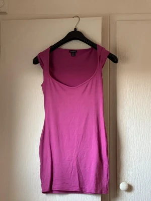 Rosa kort klänning från Bonprix - En enkel och snygg rosa kort klänning från Boohoo. Klänningen är ärmlös med djup rundringning och har en tight passform som framhäver figuren. Tillverkad i mjuk bomull, perfekt för varma dagar eller när du vill ha en chill look.