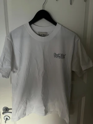 Notre Succes T-shirt - Amalfi Sails tryck - Vit t-shirt från Notre Succes med text på bröstet och stort Amalfi Sails-tryck på ryggen med citronmotiv. Klassisk passform och rund hals. Perfekt för dig som gillar stilrena plagg med snygga detaljer.