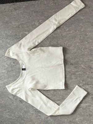 Vit ribbad långärmad topp  - Vit ribbad topp. Modellen är croppad med lång ärm och rundad halsringning. Aldrig använd.