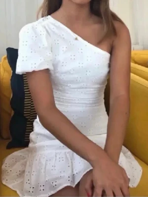 Vit oneshoulder klänning från bershka - Säljer en super fin vit kortklänning från Bershka med oneshoulder och broderade detaljer. Perfekt inför sommaren eller till student/skolavslutning!