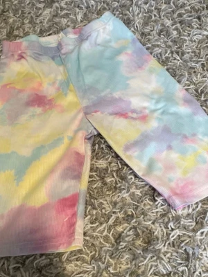 Pastellfärgade ribbade shorts - Säljer ett par ribbade shorts i pastellfärger med tie-dye känsla. Färgerna går i ljusblått, rosa, gult och lila. Modellen är midwaist och materialet känns mjukt och stretchigt, perfekt för sommarens alla äventyr.